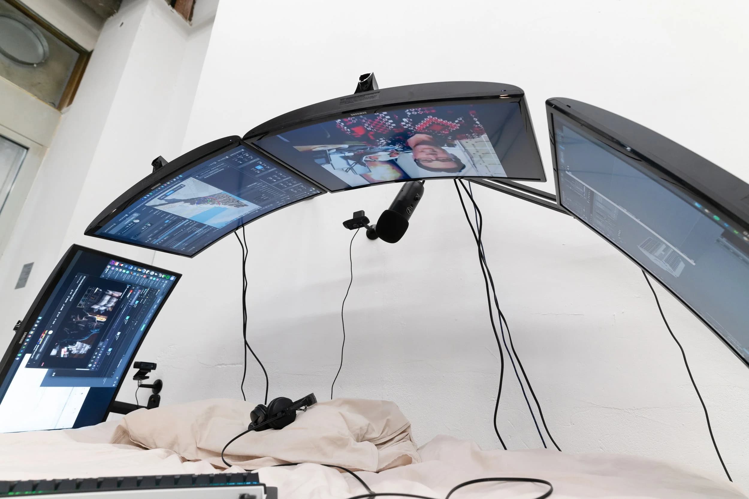 Bed PC: an array of monitors and a streaming microphone above the pillows